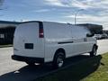 A white 2015 Chevrolet Express van with a plain exterior and chrome wheels parked on the side of the street