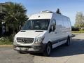 A white 2016 Mercedes-Benz Sprinter van with a high roof and a black front grille parked on a concrete surface