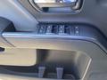 A close-up view of the door panel in a 2014 GMC Sierra 1500 featuring window control buttons and textured black plastic elements
