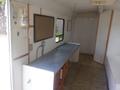 Interior of a 2004 Royal 18 Foot Office Trailer featuring a gray countertop with cabinets underneath and a bulletin board on the wall
