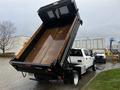 A 2021 Ford F-550 dump truck with its bed raised, revealing a metal dump bed with a wooden edge