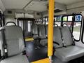 Interior of a 2016 Ford Econoline with gray vinyl seats arranged in rows and a yellow pole for support in the center of the aisle