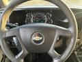 Steering wheel of a 2017 Chevrolet Express with a Chevrolet logo and various controls visible on the side and dashboard gauges in the background