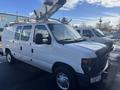 A white 2008 Ford Econoline van with a ladder rack on top parked in a lot