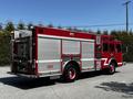 A red 2006 Emergency One Fire Truck with multiple compartments and a visible fire hose connection on the rear side