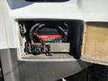 A close-up of the battery compartment in a 2017 Chevrolet Express showing a red battery with attached cables and a battery disconnect switch