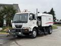 A 2009 UD Trucks UD 3300 street sweeper with a white and red body features front brushes and a large suction system on the side