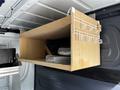 A wooden storage box with hooks mounted inside a van with tools and supplies visible inside the box