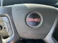 Steering wheel of a 2016 GMC Savana with the GMC logo in the center and buttons for controls on the left side