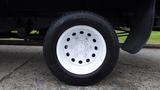 A white wheel of a 2018 Ford Transit with a steel rim and black tire showcasing several bolt holes in the center