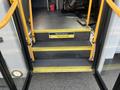 A set of steps leading into a 2018 Chevrolet Express bus with yellow handrails and a warning sign about watching your step