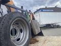 A 2017 Ford F-550 truck with a large wheel in the foreground and a flatbed attached featuring various tools and equipment secure for transport