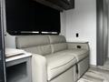 A light gray sofa with a reclining feature set against a wall with black window shades in a modern interior space