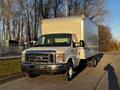 A 2017 Ford Econoline with a gray box truck body parked on a road