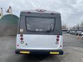 A rear view of a 2017 Chevrolet Express bus featuring a white and gray exterior with brake lights and a signage area above the back window