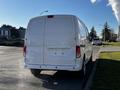 A white 2017 Nissan NV200 van parked on the side of the street with a blank rear license plate and no visible branding or logos