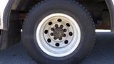 Close-up of a white wheel with multiple bolts and a black tire on a 2006 Ford Econoline