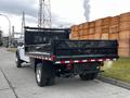 A 2019 Ford F-550 truck with a flatbed and black tarp cover at the rear parked on a gravel surface