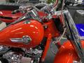 A 2024 Harley Davidson Fat Boy motorcycle with a glossy red tank chrome accents and a prominent logo on the side