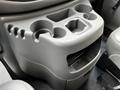 A gray console with multiple cup holders and a storage compartment designed for a 2004 Ford Econoline
