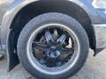 Close-up of a black wheel and tire of a 2017 RAM 1500 featuring a shiny multi-spoke alloy rim and rugged all-terrain tread pattern