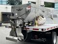 A 2011 Ford F-550 truck equipped with a metal salt spreader attached to the bed with hoses and a container on the side