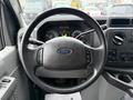 A steering wheel of a 2013 Ford E-350 featuring the Ford logo and control buttons for various functions