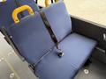 A blue upholstered seat with a black seatbelt secured to a sturdy frame designed for bus or van seating