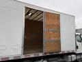 A white 2017 Freightliner M2 106 box truck with a partially opened wooden side door revealing a spacious interior with wooden panels