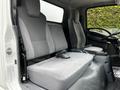 Interior view of a 2018 Isuzu NPR with two gray fabric seats and a central console in the front cabin