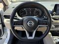Steering wheel of a 2021 Nissan Altima with controls and the Nissan logo prominently displayed