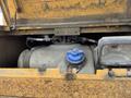 A 2018 John Deere 350 engine compartment showing a gray fuel tank with a blue cap and various pipes connected to it