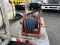 A flat deck trailer equipped with a reel holding blue and black hoses designed for hot water weed control