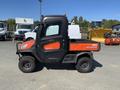 2018 Kubota ATV with an orange and black exterior featuring a cargo bed and rugged tires designed for off-road use