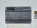 A silver label with the text "SOUTH" and details about a vehicle, including make, model, serial number, inspection date, and contact information for Kova Engineering South Ltd