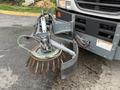 A 2009 UD Trucks UD 3300 equipped with a front-mounted street sweeper brush and attached mechanical components for cleaning surfaces