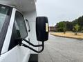 A 2020 Chevrolet Express van with a large side mirror visible in the foreground, showing droplets of water on its surface