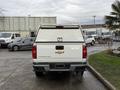 A white 2019 Chevrolet Colorado pickup truck is parked with its tailgate closed and a camper shell on the bed, featuring the Chevrolet logo on the rear gate