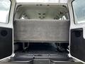 Interior view of the back of a 2004 Ford Econoline showing a large gray upholstered bench seat and a black floor mat