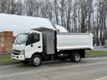 A 2014 Hino 195 truck with a white dump bed and an open compartment on the side parked on a street