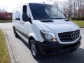 A 2016 Mercedes-Benz Sprinter van in white with a sleek design featuring a prominent front grille and large side mirrors parked on a pathway