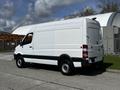 A 2017 Mercedes-Benz Sprinter van with a white exterior and black accents parked in a lot showing its side profile and rear