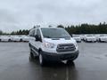 A 2017 Ford Transit van in white color parked in the foreground with its doors and windows closed