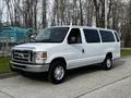 White 2014 Ford Econoline van with large windows and a front grille parked in a lot