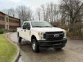 A 2017 Ford F-350 SD pickup truck in white with a crew cab and a flatbed design parked on a wet surface