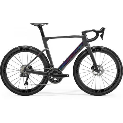 A 2026 Merida Reacto 9000 road bike featuring a sleek design with a black frame and colorful branding along the side high-performance wheels and disc brakes