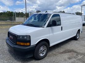 A 2023 GMC Savana van with a white exterior and black grille parked in a gravel lot