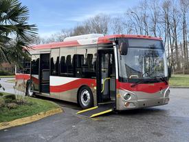 A red and silver 2016 Grande West Vicinity bus with an open door and a wheelchair ramp extended