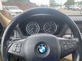 A close-up view of the steering wheel and dashboard of a 2009 BMW X5 featuring gauges and control buttons