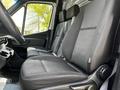 The interior of a 2020 Mercedes-Benz Sprinter featuring two driver seats in black fabric with a minimalist design and visible seat adjustments
